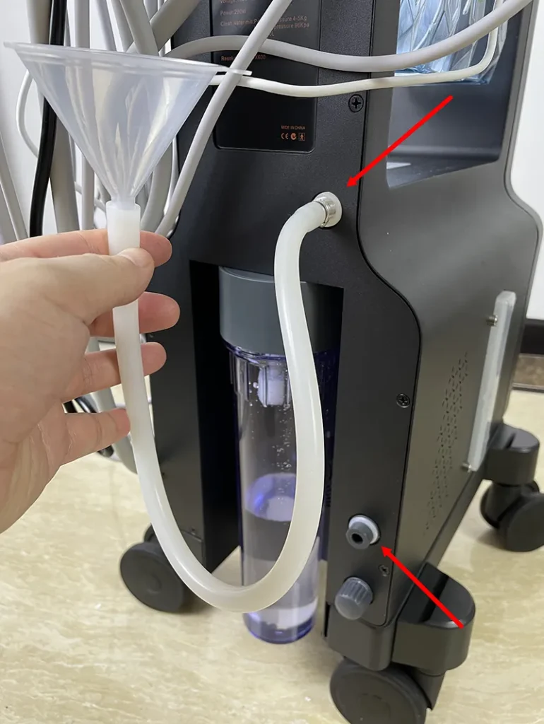 Main tenant un entonnoir pour ajouter de l'eau dans le réservoir de l'appareil hydro dermabrasion, étape préalable de préparation du matériel esthétique pour institut