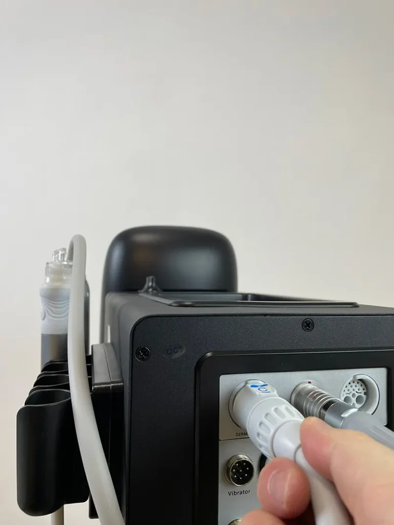 Main branchant le connecteur de la poignée hydro dermabrasion sur la prise arrière de l'appareil hydro dermabrasion, étape de raccordement pour matériel de soins visage professionnel