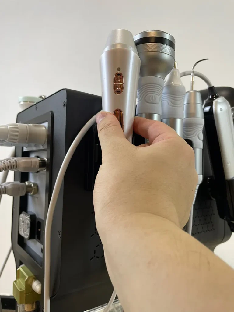 Main plaçant la poignée d'analyse cutanée sur le support latéral de l'appareil hydro dermabrasion, étape d'installation accessoire diagnostic peau pour institut de beauté professionnel