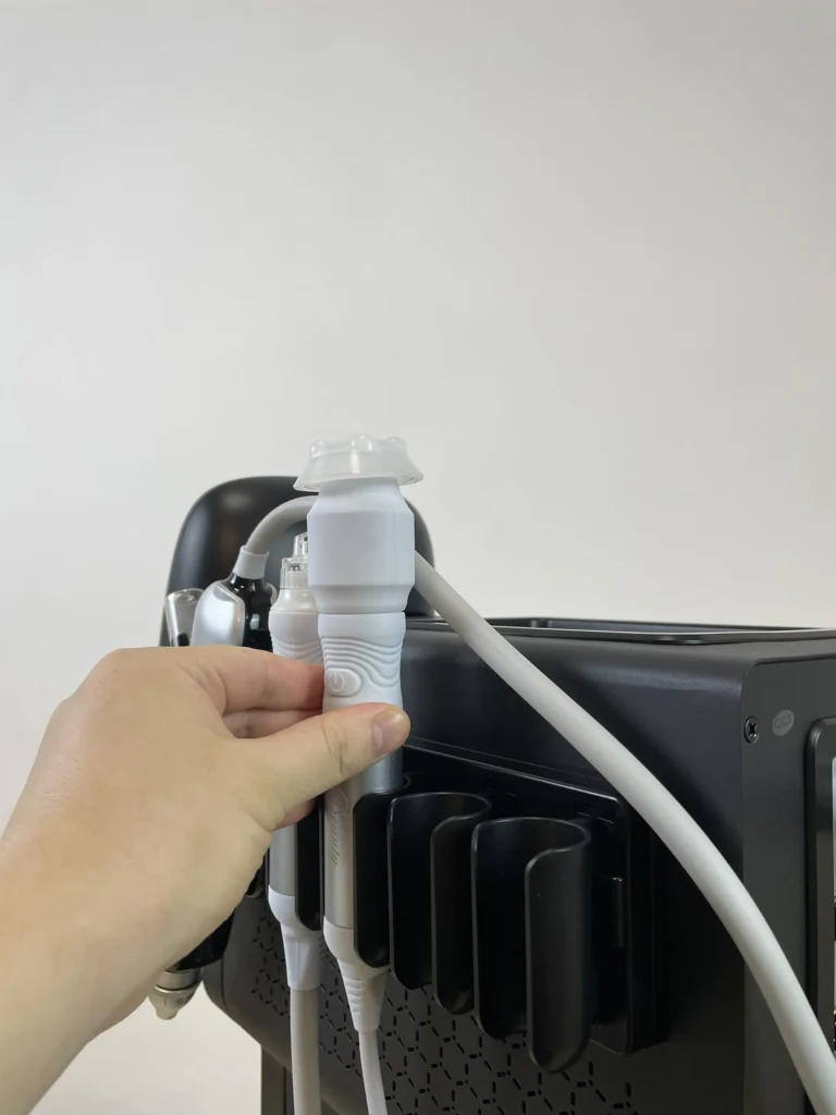Main plaçant la poignée d'oxygénation sur le support latéral de l'appareil hydro dermabrasion, étape d'installation accessoire de soin oxygène visage institut