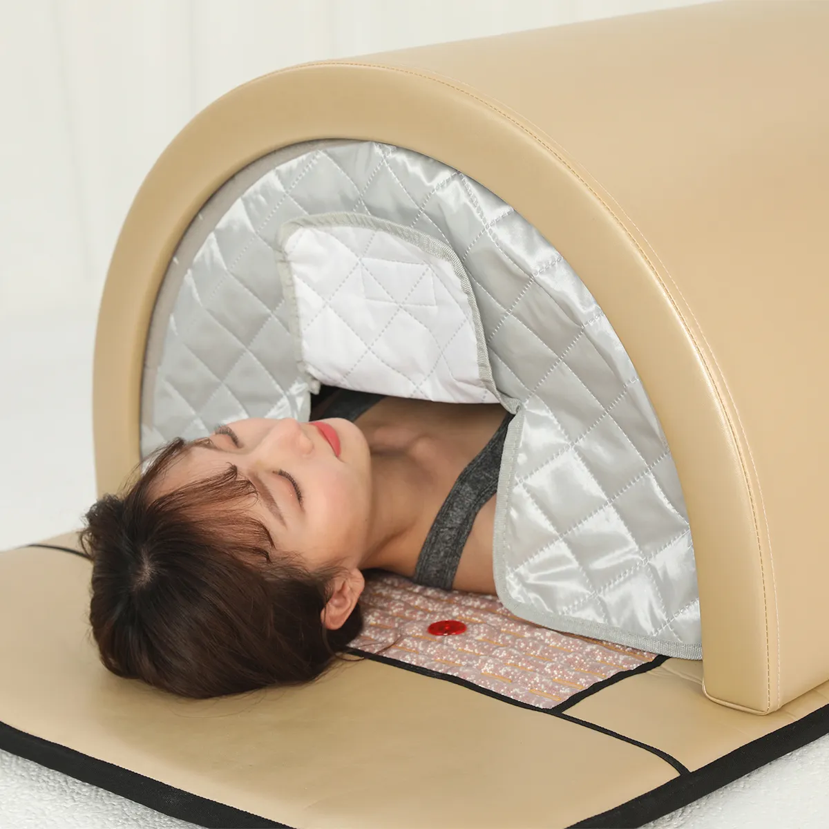 Close-up shot of woman enjoying far infrared heat therapy inside a beige infrared sauna dome with quilted interior lining