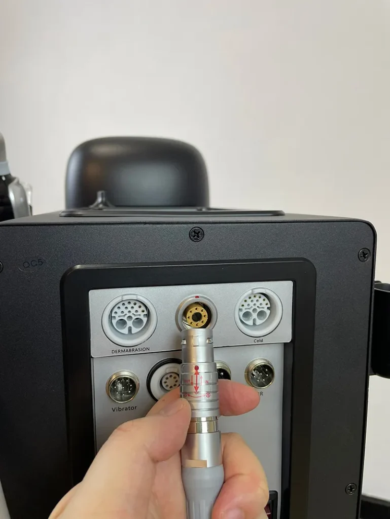 Hand plugging jet peel handpiece metal connector into port of 10 in 1 hydradermabrasion machine, wiring connection installation step for spa facial equipment