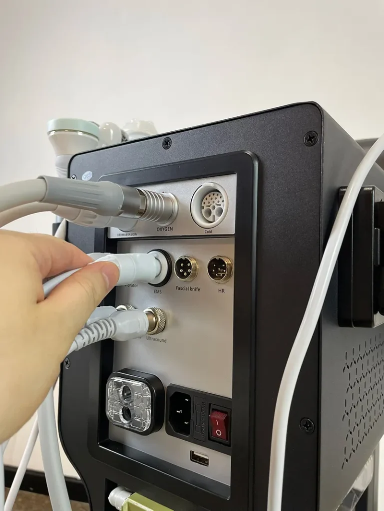 Hand plugging signal connector of mesotherapy handpiece into rear port of 10 in 1 hydradermabrasion machine, wiring connection installation step for salon nutrient infusion facial equipment