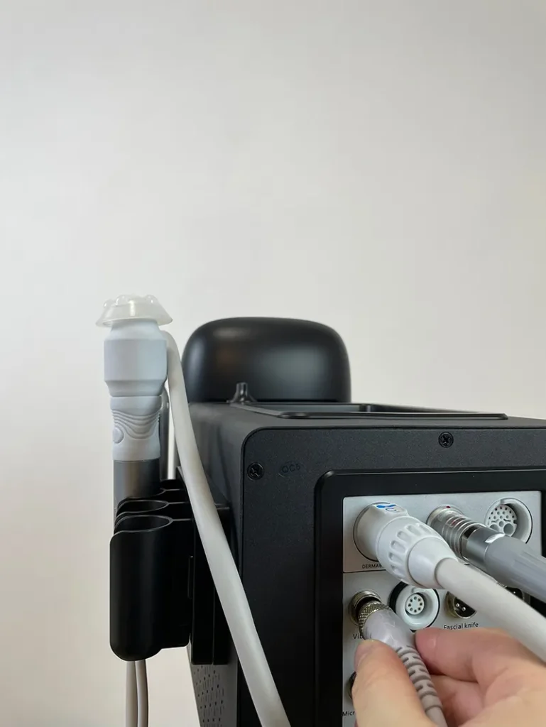Hand plugging the connector of oxygenation handpiece into rear port of 10 in 1 hydradermabrasion machine, wiring connection installation step for salon facial equipment