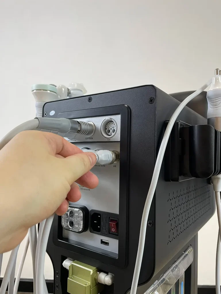 Hand plugging signal connector of radio frequency handpiece into rear port of 10 in 1 hydradermabrasion machine, wiring connection installation step for anti-aging facial spa equipment